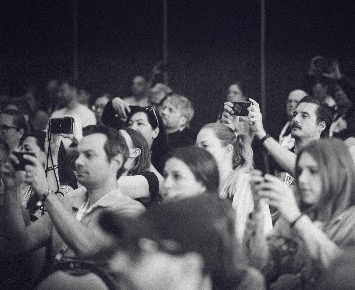 Ein Publikum auf einer Konferenz hält Telefone hoch, um Slides zu fotografieren.